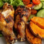 Roasted chicken with sweet potato and fresh salad served on a plate.